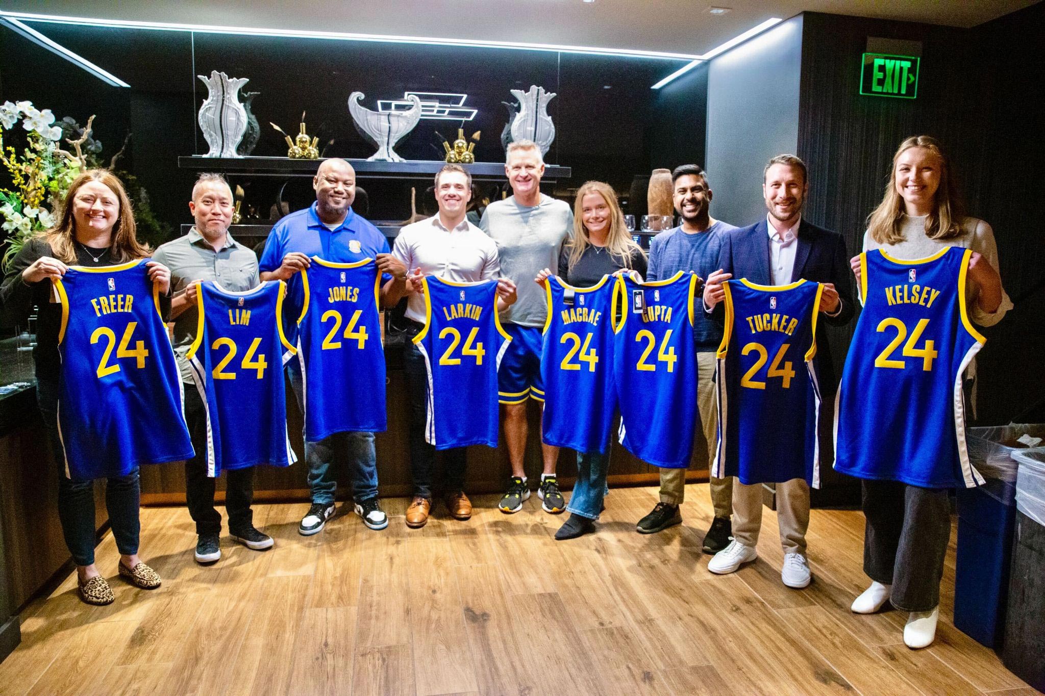 Employees showing off custom Warriors jerseys with their own names on the back.