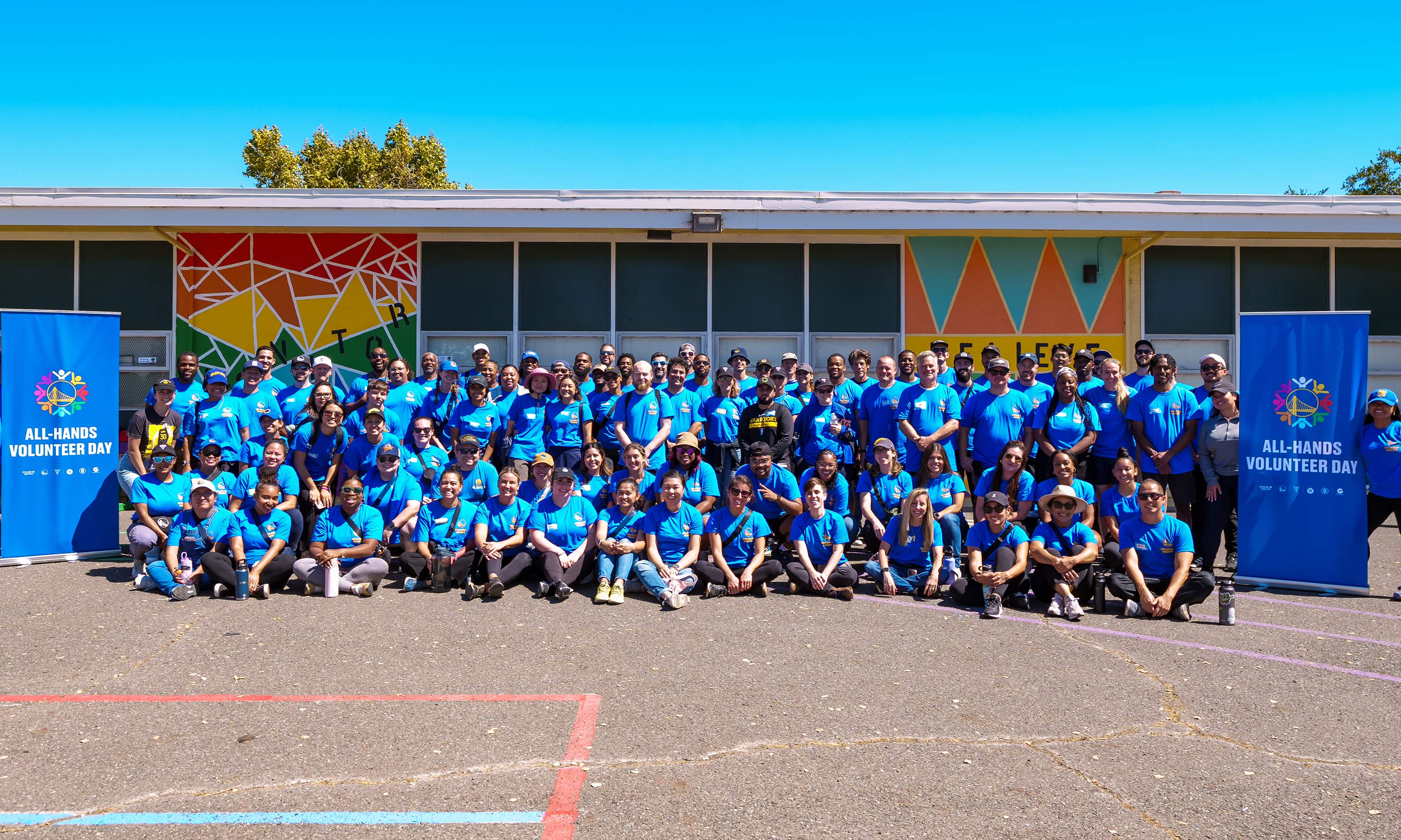 All employees in blue volunteer shirts smiling to the camera during All-Hands Volunteer Day.