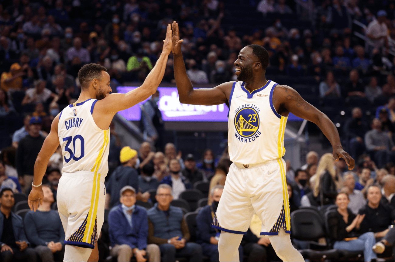 Steph Curry and Draymond Green high-fiving on the court.