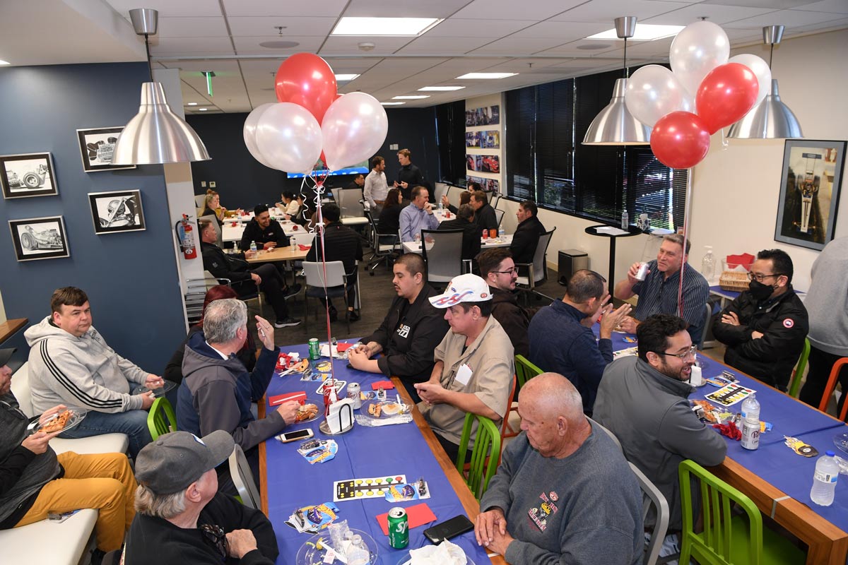 A celebratory office party at NHRA with people sitting at tables decorated with balloons.