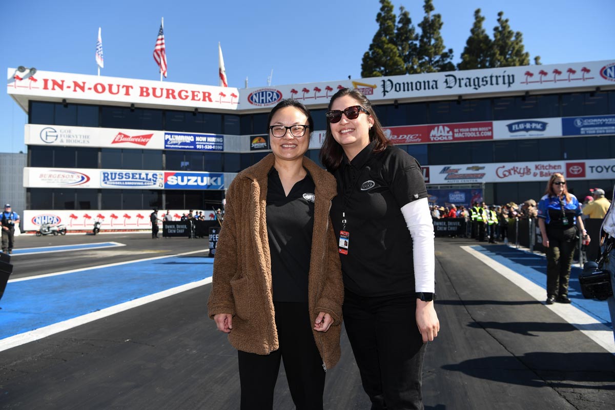 Two women employees standing on a racetrack at the Pomona Dragstrip