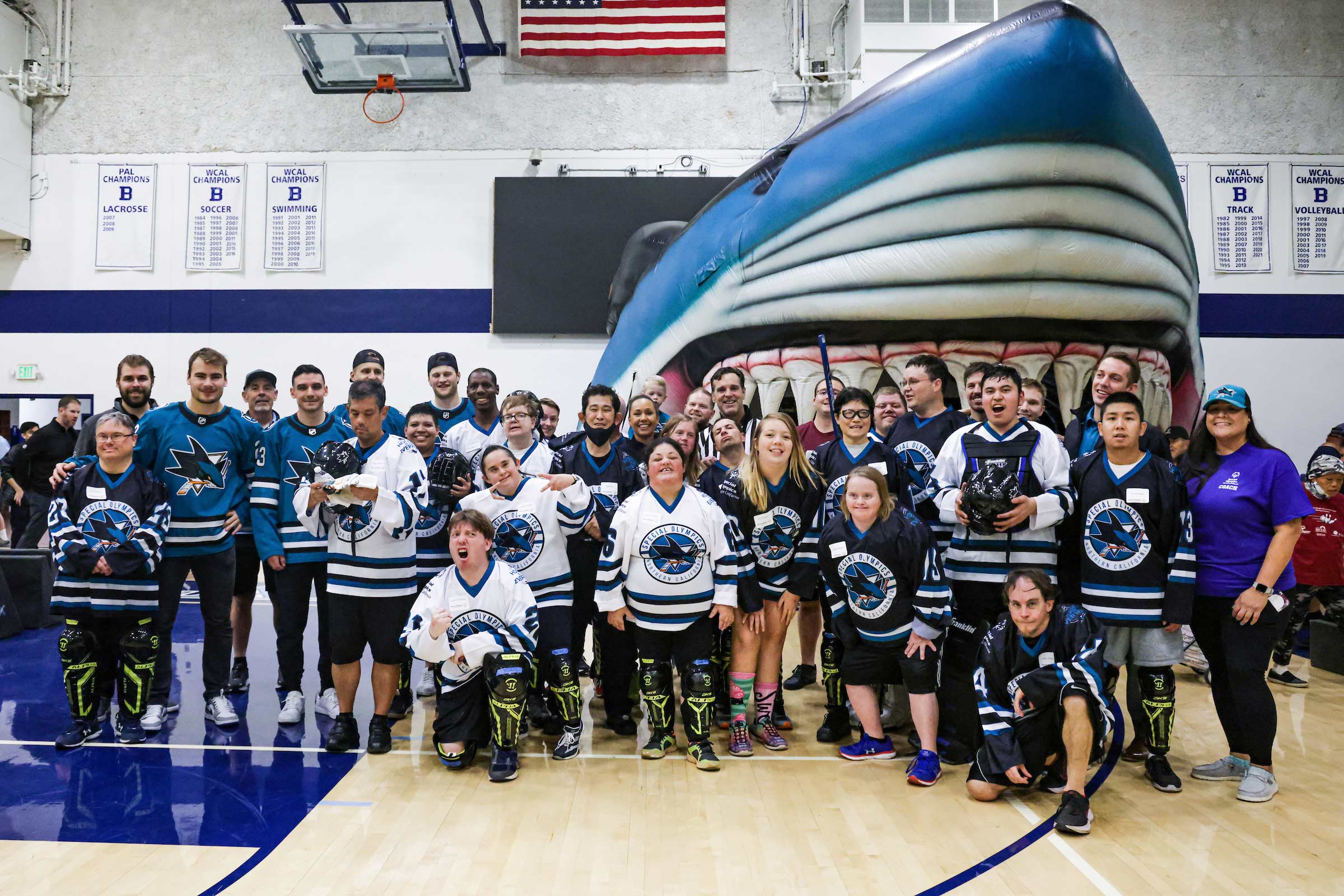 Sharks players in a gymnasium with hockey players from the Special Olympics of Northern California dressed in Sharks gear