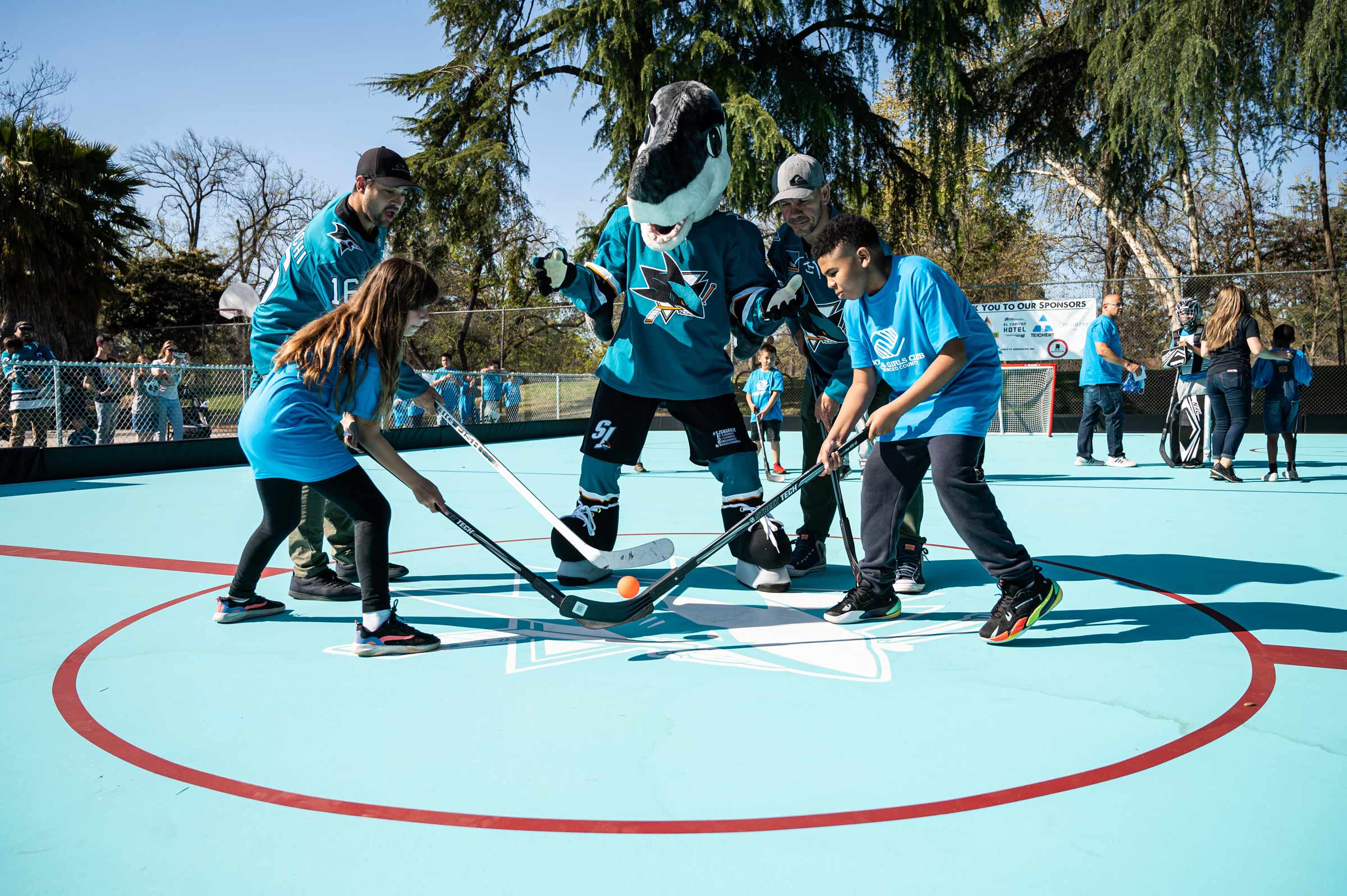 The start of a children's street hockey game with the Sharks mascot acting as referee