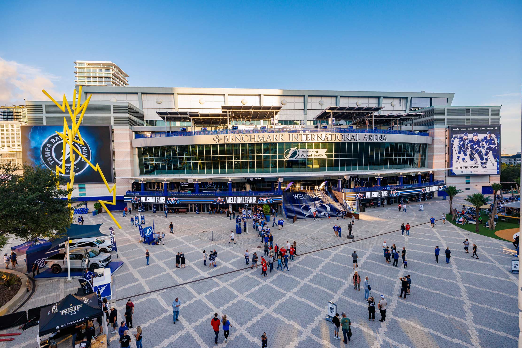 The front of the Benchmark International Arena with people walking in the foreground