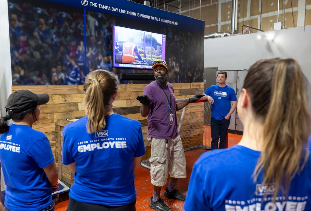 A man giving instructions to a group of employees at a volunteer event