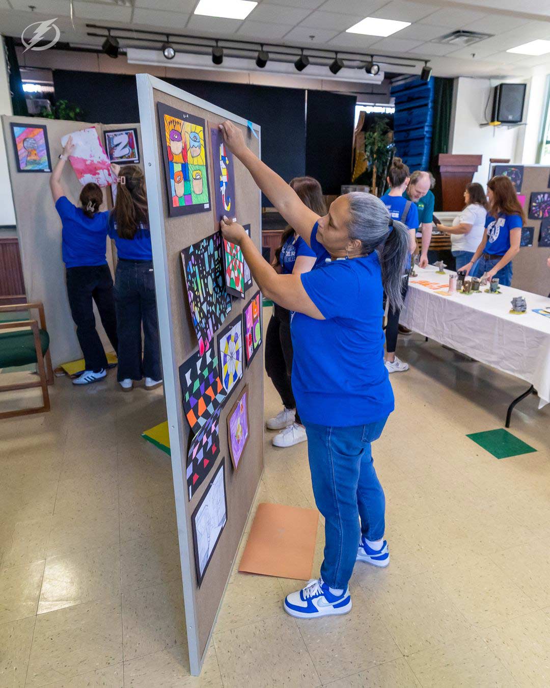 A woman putting up artwork on a wall