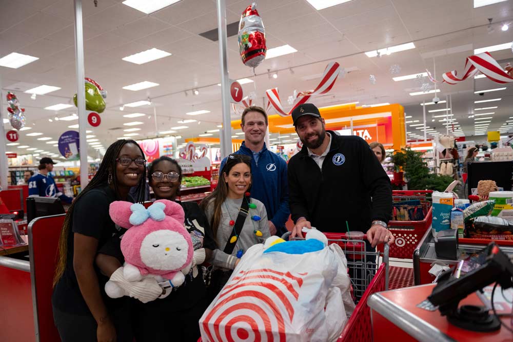 A group of employees in front of a shopping cart at Target with a large full bag of goods inside