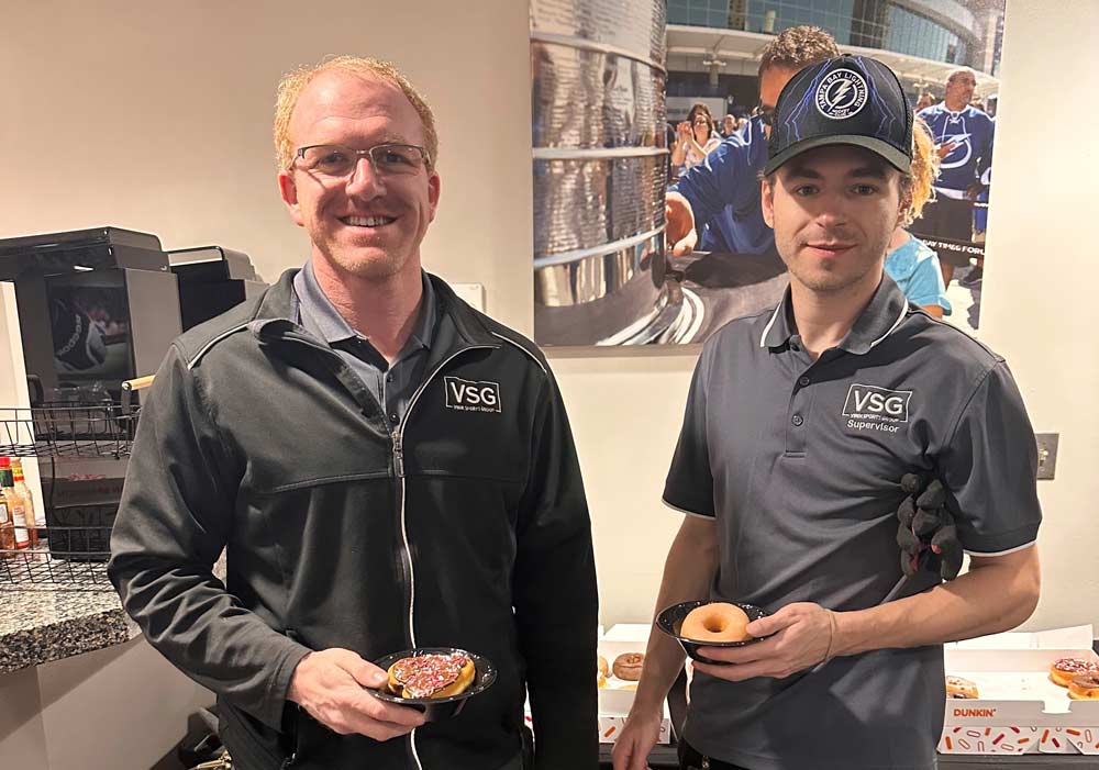 A man and a younger man in an office eating donuts