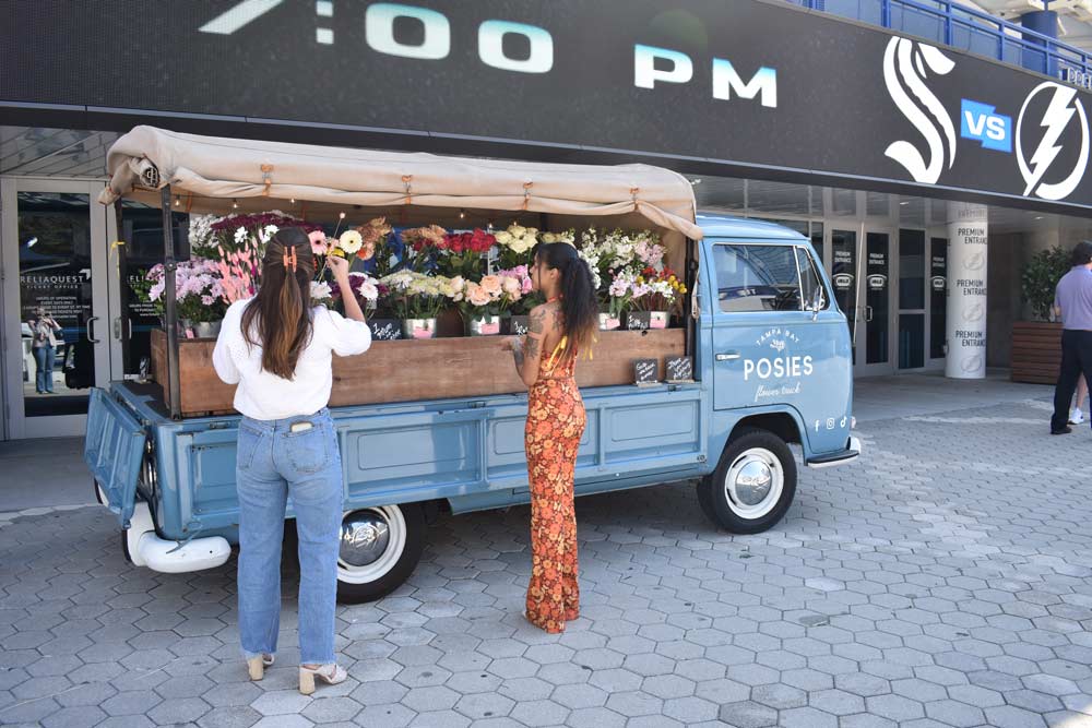Two women tending to flowers in a truck bed full of plants