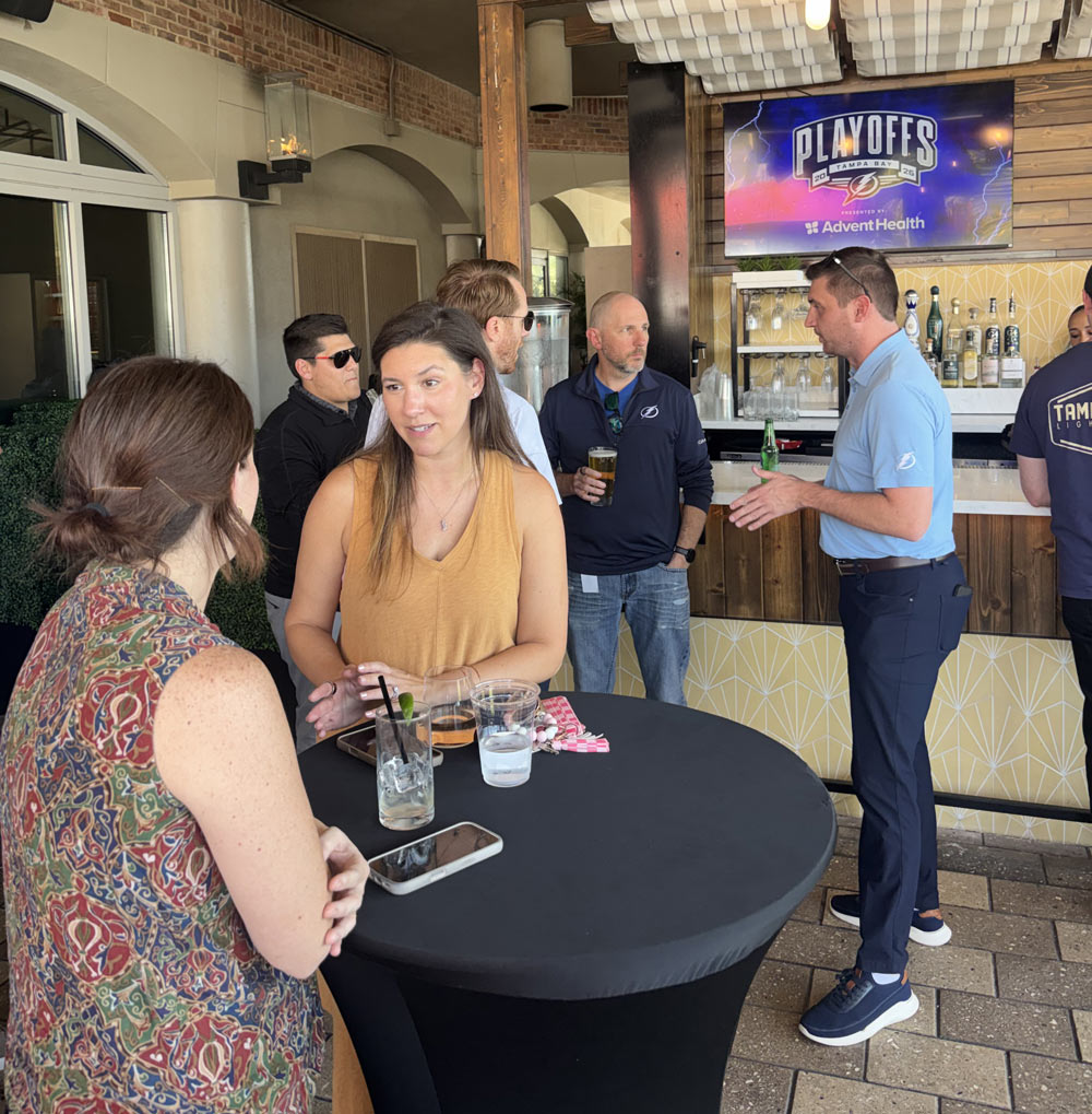 A group of men and women casually talking and drinking at a bar.