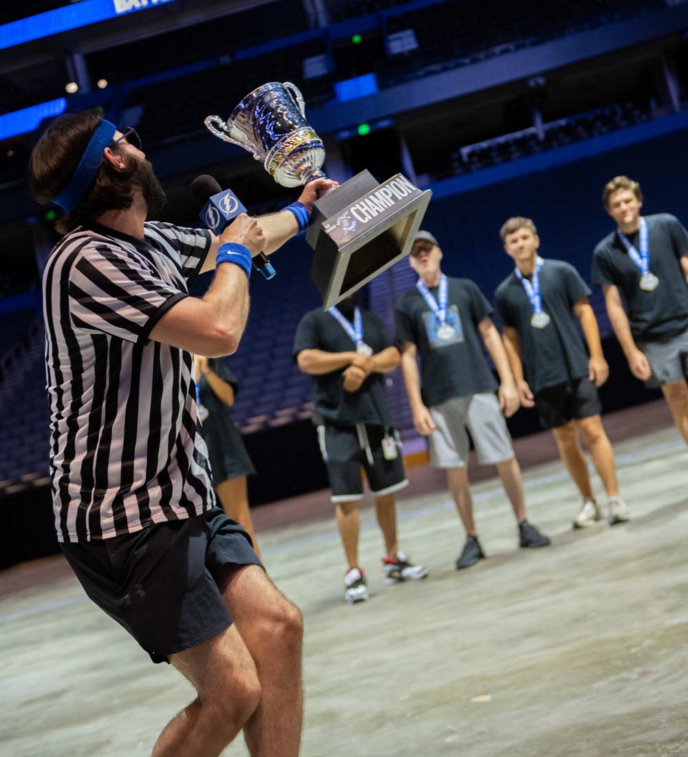 A referee holding up a trophy giving it to a group of men with medals around their necks