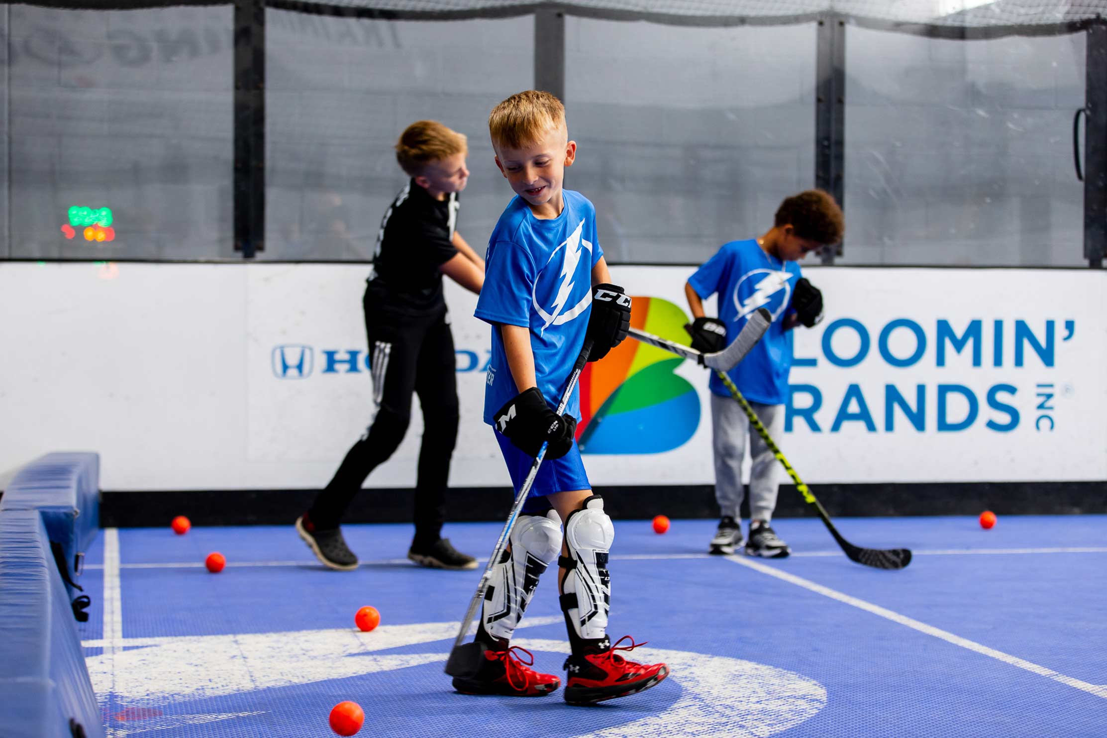 A young boy playing indoor hockey wearing a Tampa Bay Lightning t-shirt
